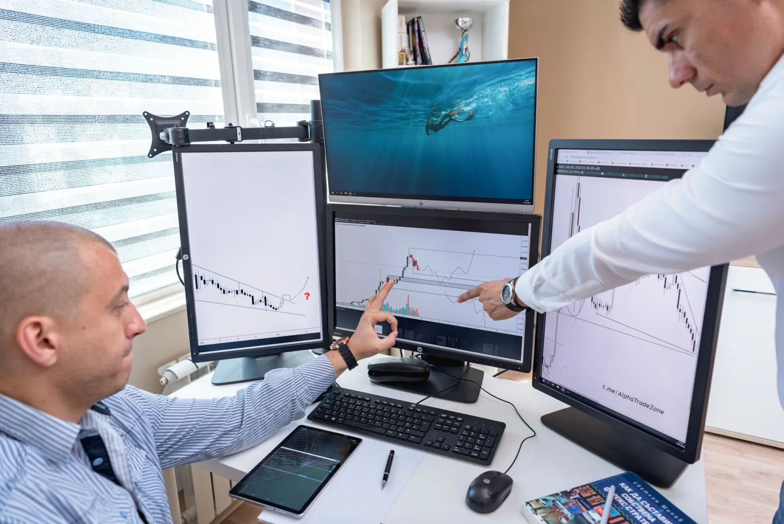 Duas pessoas analisando gráficos em várias telas de computador