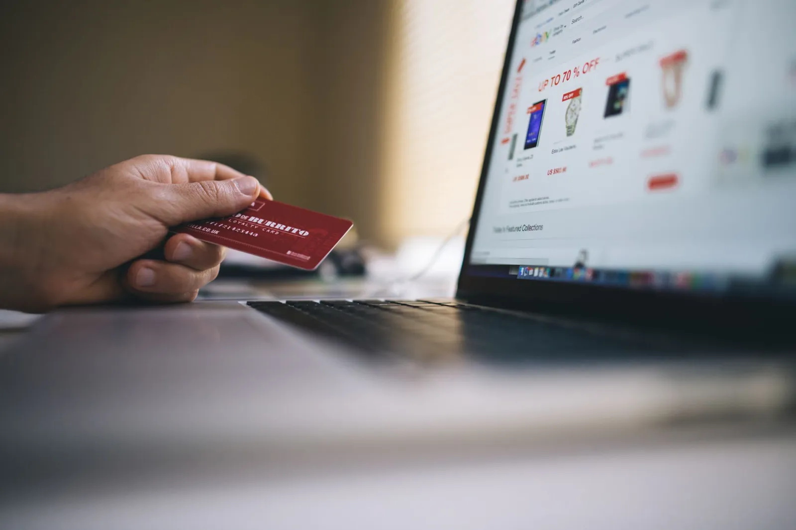 Pessoa segurando um cartão de crédito diante da tela de uma loja on-line